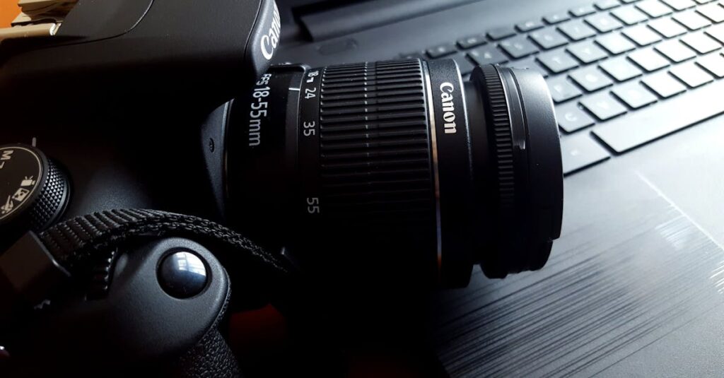 Close-up of a black DSLR camera with lens on a laptop keyboard.
